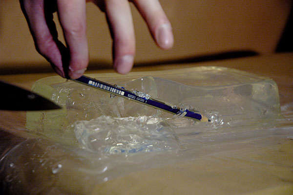 A picture of the pencil being surgically removed from the gel using a knife to cut the gel.